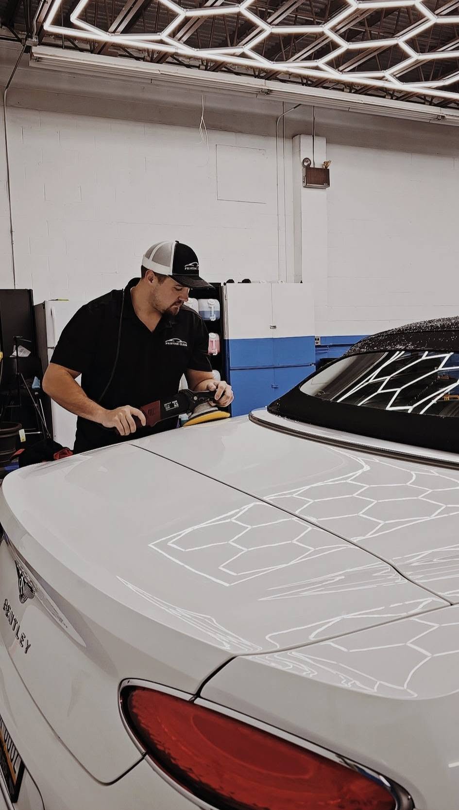 Gerard machine polishing a white Bentley under inspection lighting